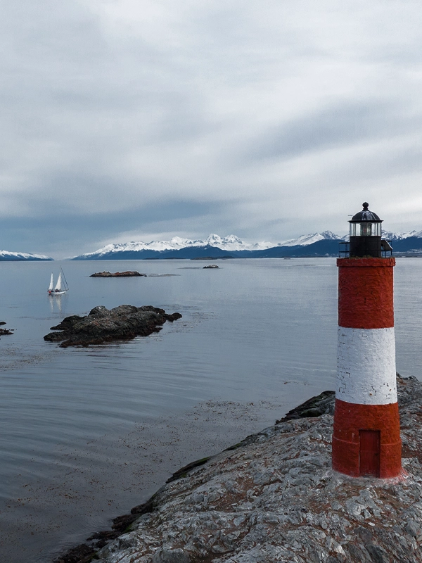 DESTINO FARO LES ÉCLAIREURS Navegação no Veleiro Ksar em direção ao Destino Faro Les Éclaireurs! Embarque em uma emocionante travessia a bordo do Veleiro Ksar, navegando pelas águas do Canal Beagle rumo ao destino Faro Les Éclaireurs, em Ushuaia, Terra do Fogo, o fim do Mundo. Descubra a majestade das paisagens fueguinas enquanto o vento acaricia seu rosto e as lendas ancestrais ganham vida. Nesta viagem, a natureza selvagem vai cativá-lo, transformando o barco em seu santuário de tranquilidade e aventura. Cada instante a bordo é uma oportunidade para explorar, refletir e conectar-se com a essência do ambiente. Em cada porto, uma nova história espera ser descoberta, uma experiência única pronta para ser vivida. Junte-se a esta fascinante odisseia marítima e deixe que o Veleiro Ksar seja seu companheiro nesta jornada rumo ao desconhecido. NAVEGAÇÃO AO FARO LES ÉCLAIREURS Explore o Canal Beagle com o Veleiro Ksar. O veleiro mais confortável para navegações com destino ao Faro Les Éclaireurs. Embarque em uma navegação única rumo ao Faro Les Éclaireurs em Ushuaia, Terra do Fogo, com o Veleiro Ksar, cruzando as águas do Canal Beagle no fim do Mundo. Desfrute da majestade da natureza fueguina e viva momentos inesquecíveis em alto-mar. Junte-se à nossa odisseia marítima e descubra a beleza virgem deste destino remoto com nossa atenção personalizada e serviços exclusivos. Bem-vindo a uma aventura onde cada momento é uma experiência única no coração da Patagônia argentina. DADOS DO FARO LES ÉCLAIREURS Embarque no Veleiro Ksar para explorar o Canal Beagle em uma travessia de três dias ou Full Day até o Faro Les Éclaireurs, o Faro do Fim do Mundo. Descubra fauna e paisagens espetaculares. Uma aventura inesquecível no extremo sul da Patagônia te espera! Descubra a magia das Navegações ao Faro Les Éclaireurs, erroneamente chamado de 'Faro do Fim do Mundo', no impressionante Canal Beagle da Terra do Fogo, Argentina! Este icônico farol, localizado no ilhote NE do conjunto de ilhotes Les Éclaireurs, é uma joia que você não pode perder durante sua visita a Ushuaia. Imagine navegar pelas águas do Canal Beagle, cercado por paisagens espetaculares, enquanto você se aproxima dessa majestosa estrutura. Com sua torre troncocônica de tijolos, pintada em vibrantes faixas brancas e vermelhas, o farol se destaca como um símbolo de orientação para os navegadores nessas águas tumultuadas. Uma vez que você chegar, será recebido pela imponente presença do farol, com sua lanterna brilhando a 22,5 metros acima do nível do mar, emitindo flashes de luz branca e vermelha que dançam no horizonte marinho a cada 5 segundos. Não perca a oportunidade de capturar esse momento único em suas fotografias. A história por trás das Navegações Les Éclaireurs também é fascinante. Nomeados pelo Capitão de Fragata Luis Fernando Martial durante a expedição francesa La Romanche nos anos 1882-1883, esses ilhotes guardam segredos e lendas que te transportarão a épocas passadas de exploração e aventura. Embora o farol esteja fechado ao público, sua presença continua sendo um ponto de referência icônico na baía de Ushuaia. Desde a água, você terá a oportunidade de admirar sua beleza e sentir-se parte da história marítima da região. Algumas agências de turismo em Ushuaia promovem emocionantes excursões ao farol, frequentemente sob o nome equivocado de «farol do fim do mundo». No entanto, é importante destacar que essa denominação é incorreta. O romance homônimo de Júlio Verne, que popularizou a ideia do «fim do mundo», inspirou-se realmente no Faro de San Juan de Salvamento, localizado na remota Ilha dos Estados. No entanto, apesar de sua beleza e relevância histórica, este farol não é o famoso «farol do fim do mundo» retratado por Verne. A confusão surge devido à semelhança com a região austral da Argentina e à associação do termo «fim do mundo». O Faro Les Éclaireurs, embora não seja o farol protagonista do romance de Verne, continua sendo uma visita obrigatória para os turistas que exploram a pitoresca Ushuaia e seus arredores. O Farol da Ilha dos Estados é muito mais largo e com mais superfície, já que conta com um abrigo em seu interior como uma residência. Portanto, ao planejar sua viagem a Ushuaia e seus arredores, lembre-se de que o Faro Les Éclaireurs é uma parada imperdível, mas tenha em mente que não é o famoso «farol do fim do mundo» do romance de Júlio Verne.